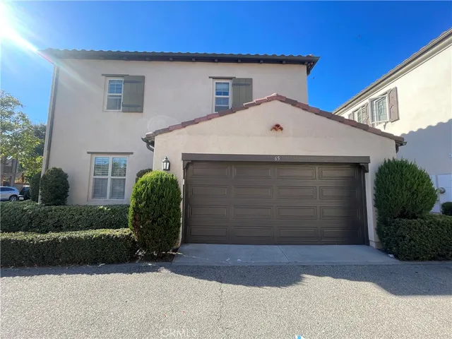 a view of a white house with a small yard and plants