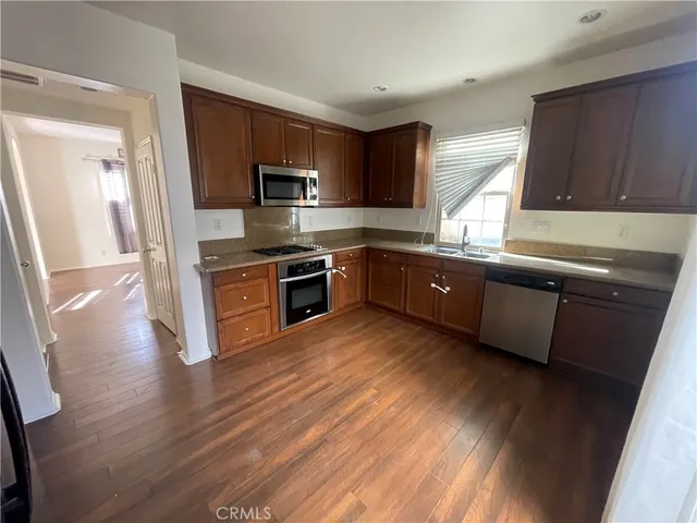 a large kitchen with wooden floors and stainless steel appliances