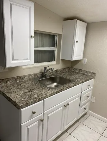 a kitchen with granite countertop a sink and white cabinets