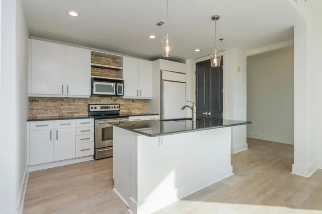 a kitchen with stainless steel appliances granite countertop a sink stove and cabinets