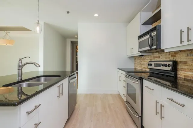 a kitchen with kitchen island granite countertop a sink and a refrigerator
