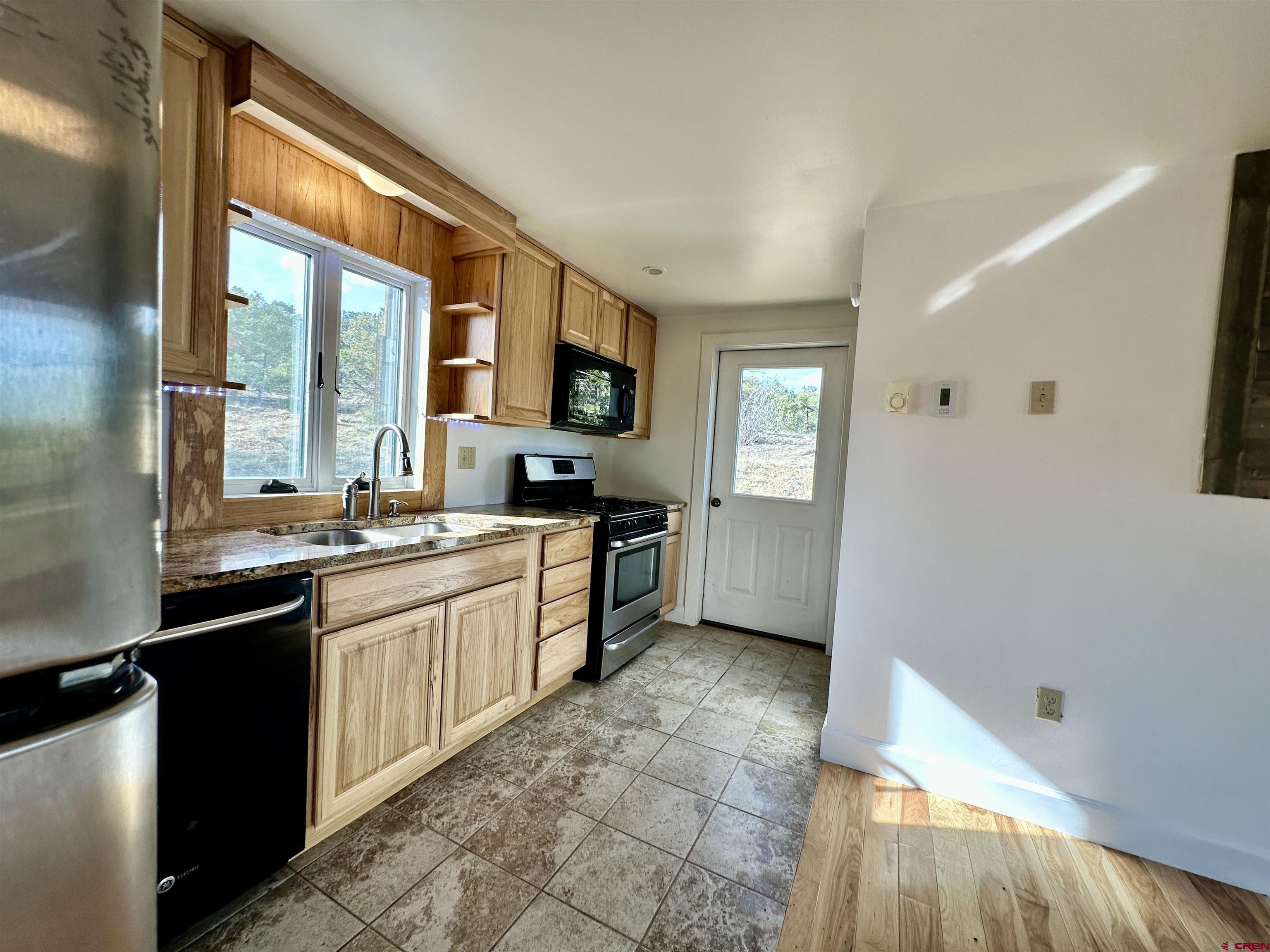 351 Loveland Road South Fork, CO 81154 - Photo 16 of 45 a large kitchen with a sink and dishwasher a stove top oven with wooden floor