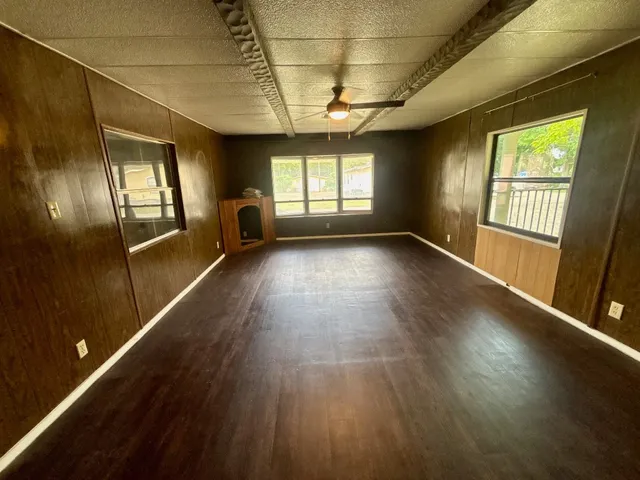 an empty room with wooden floor and windows