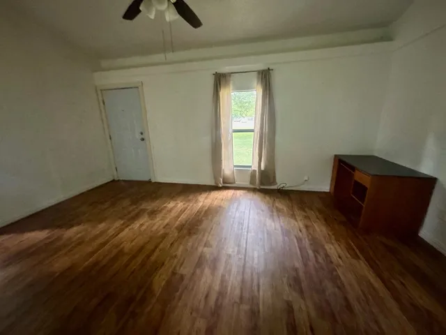an empty room with wooden floor cabinet and windows