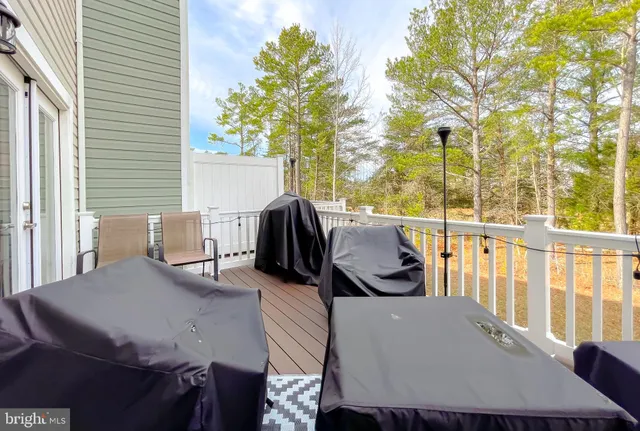 a view of a patio with table and chairs and couches with wooden floor and fence
