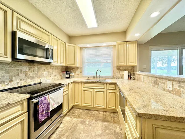 a kitchen with stainless steel appliances granite countertop a stove a sink and a microwave