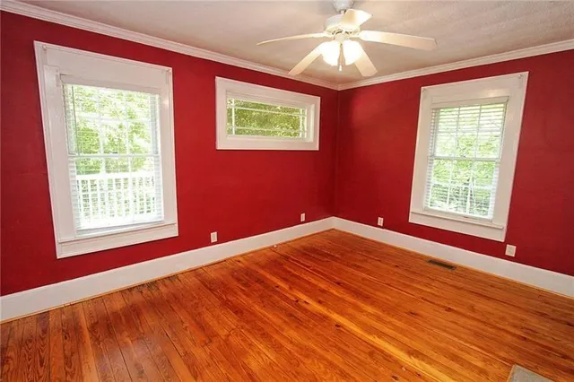 a view of an empty room with a window and wooden floor