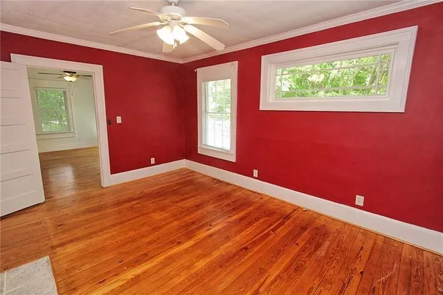 a view of empty room with wooden floor and fan