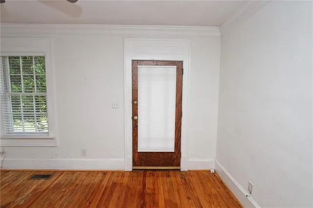 a view of an empty room with wooden floor and a window