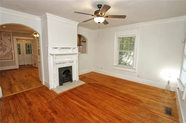 a view of a livingroom with a fireplace a ceiling fan and wooden floor
