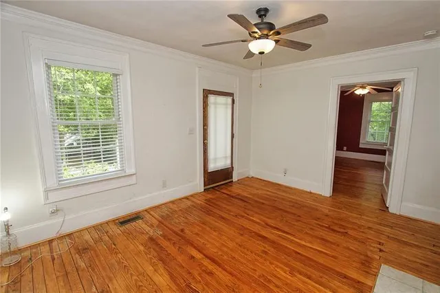 a view of an empty room with window and wooden floor