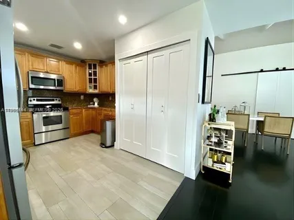 a view of a kitchen with a refrigerator a sink wooden floor and a living room