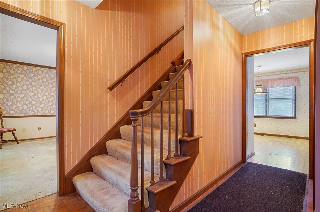 7300 Morley Road Painesville, OH 44077 - Photo 10 of 50 Stairway featuring wallpapered walls, carpet flooring, and crown molding