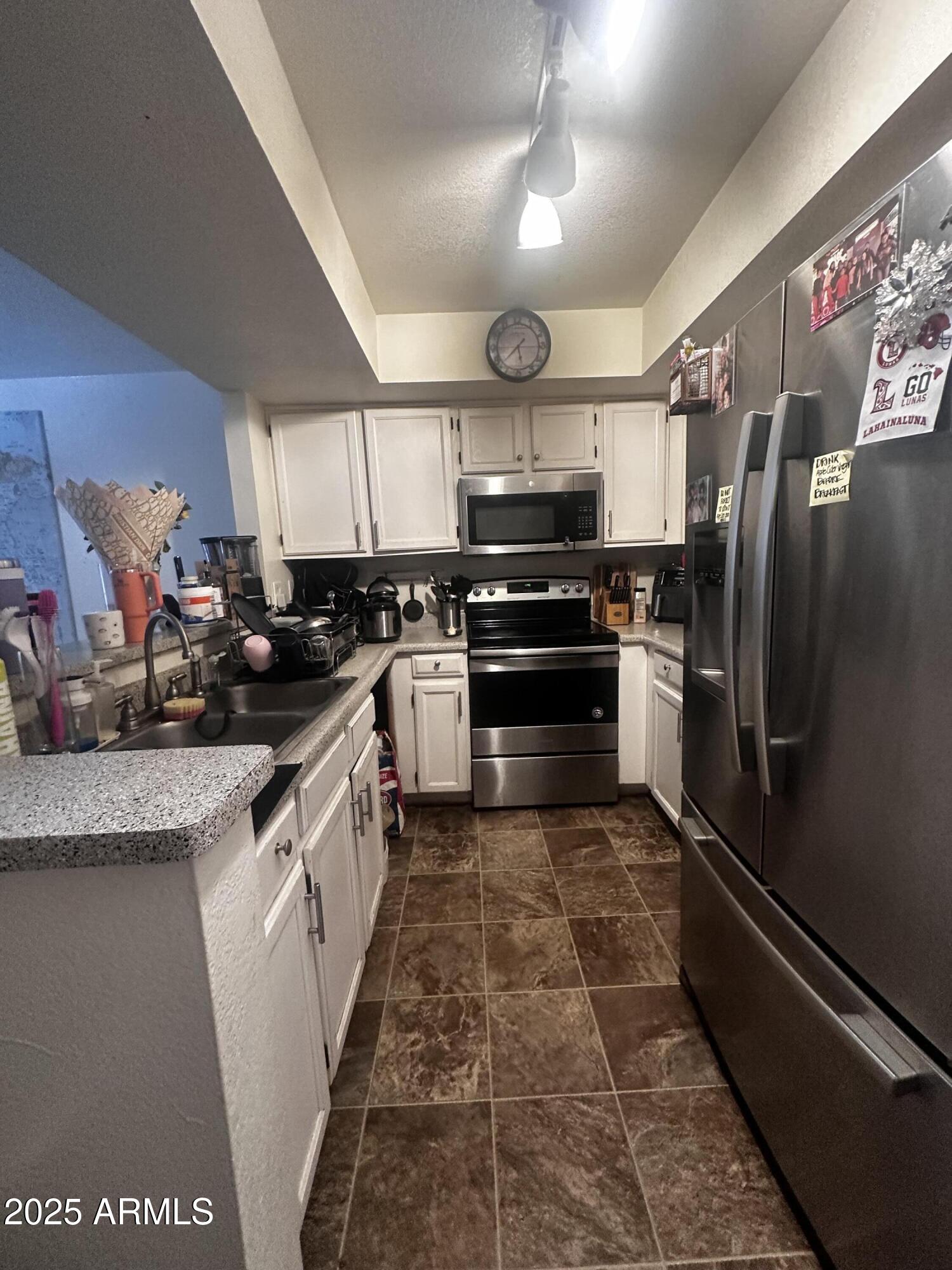 1331 West Baseline Road, Unit 219 Mesa, AZ 85202 - Photo 3 of 17 a kitchen with stainless steel appliances granite countertop a refrigerator a sink dishwasher a stove top oven a counter space and cabinets