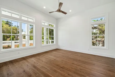 a view of an empty room with a window and wooden floor