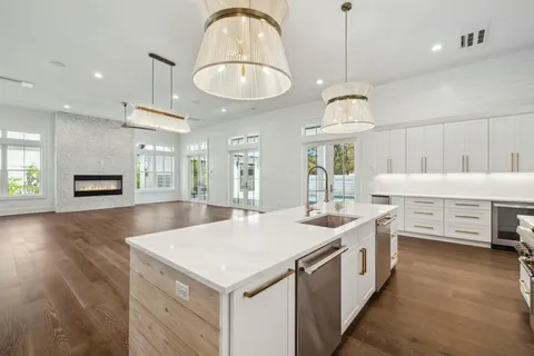 a view of an empty room with wooden floor and a kitchen