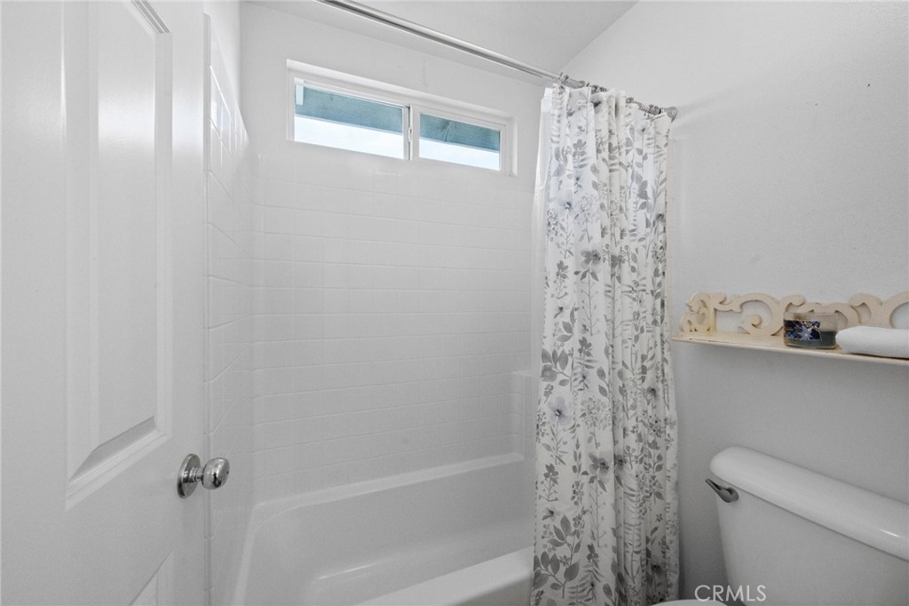 7220 Cumberland Place Rancho Cucamonga, CA 91739 - Photo 31 of 41 Hall bathroom featuring shower-in-tub combo with a bright window and vinyl plank flooring.