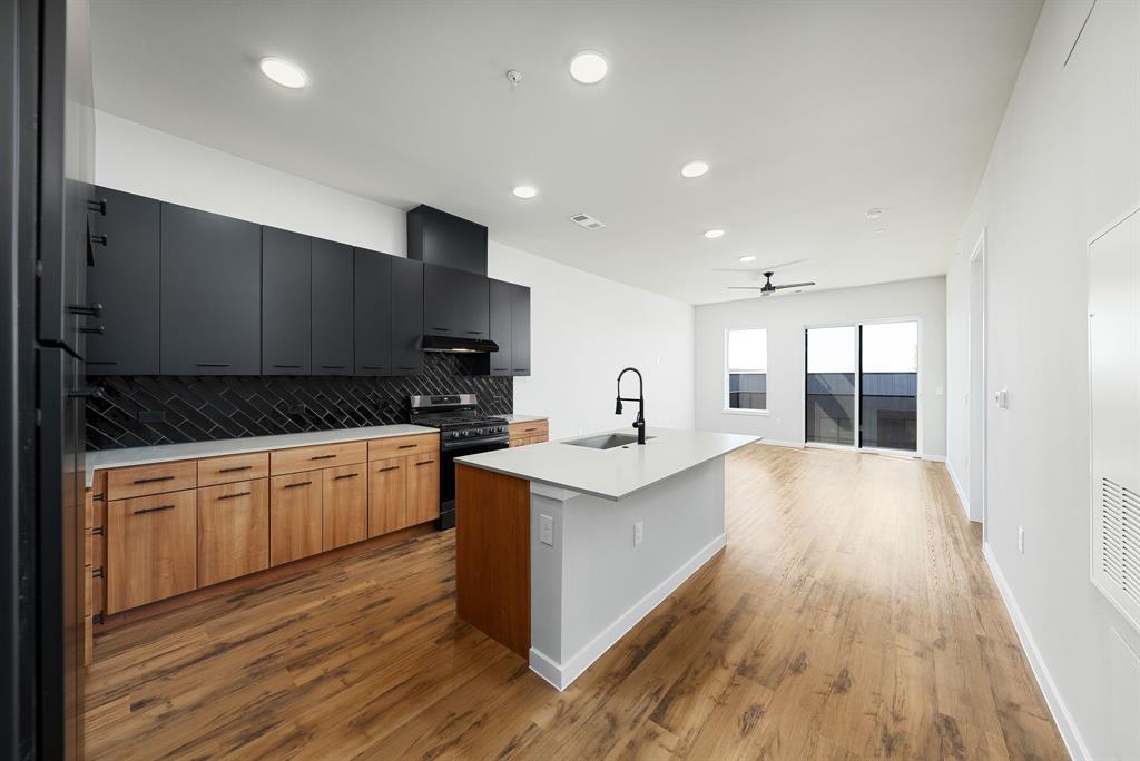 a large kitchen with stainless steel appliances a large counter top a stove and a refrigerator