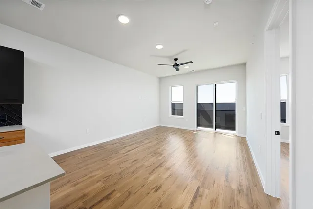 a view of an empty room with wooden floor and windows