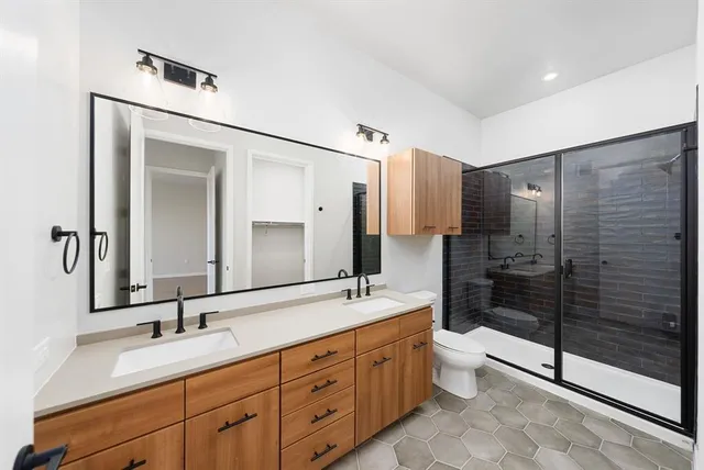 a bathroom with a double vanity sink toilet mirror and double