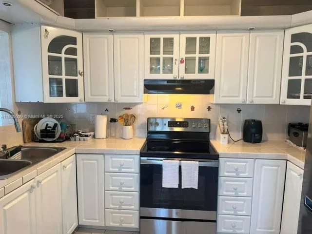 a kitchen with stainless steel appliances granite countertop a stove and a white cabinets