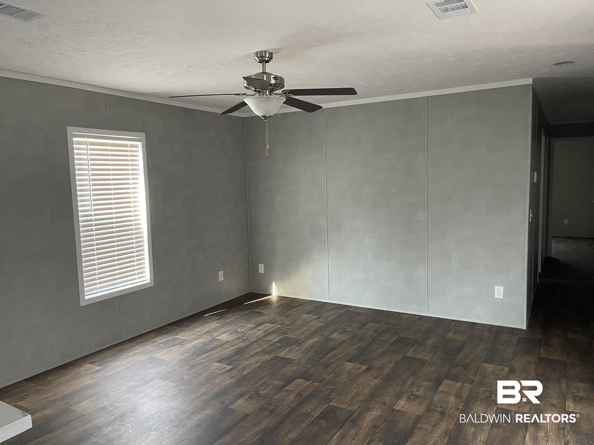 9202 Bay Pnes Road Elberta, AL 36530 - Photo 4 of 17 Spare room featuring a textured ceiling, dark wood-type flooring, ornamental molding, a decorative wall, and ceiling fan