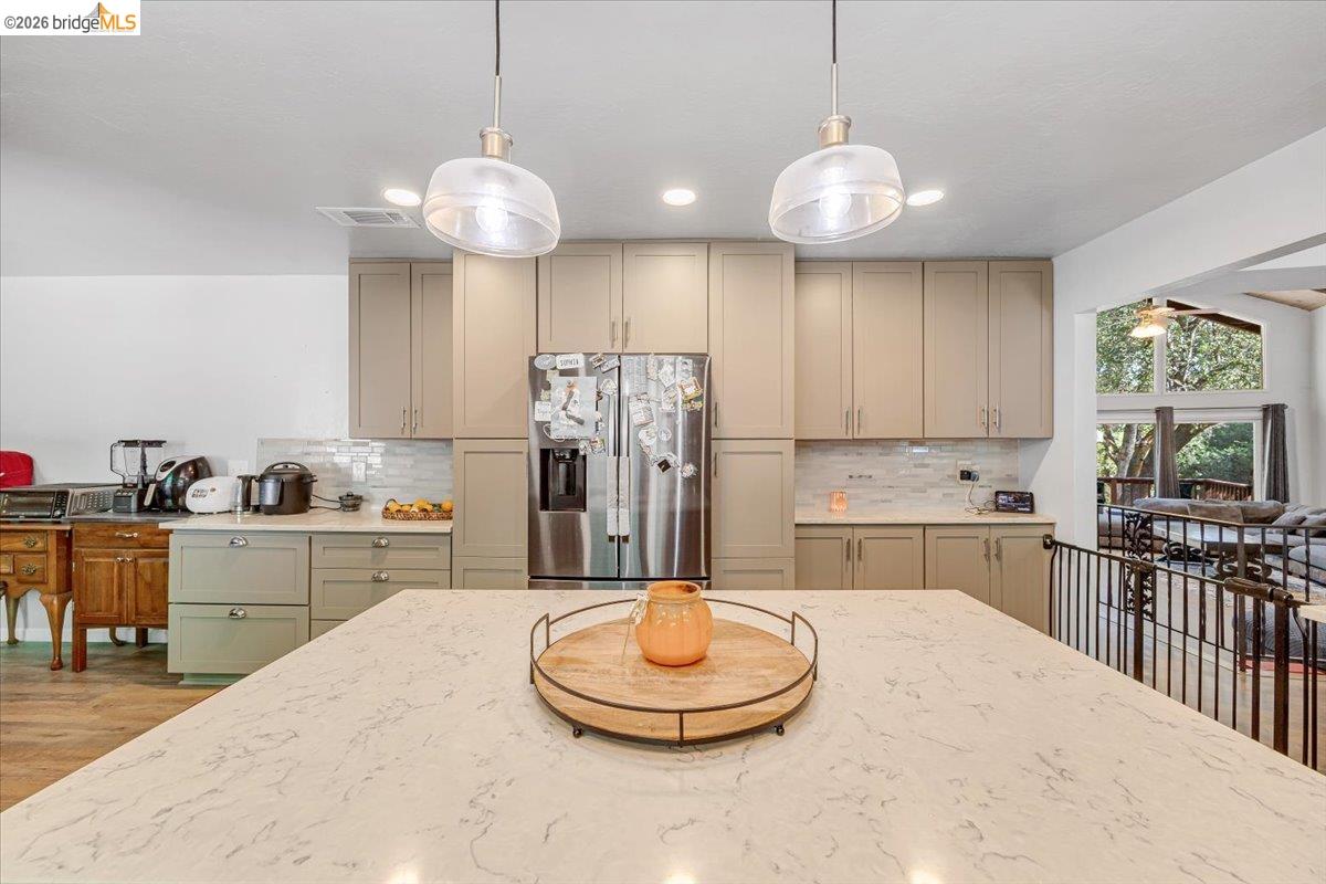 8733 Fraguero Road Sonora, CA 95370 - Photo 31 of 73 Kitchen featuring a large quartz-finish island, two pendant lights, recessed lighting, stainless steel refrigerator, and extensive cabinetry