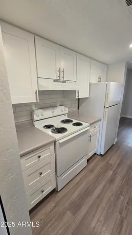 a kitchen with appliances cabinets and a wooden floor