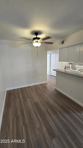 a view of kitchen and empty room with wooden floor