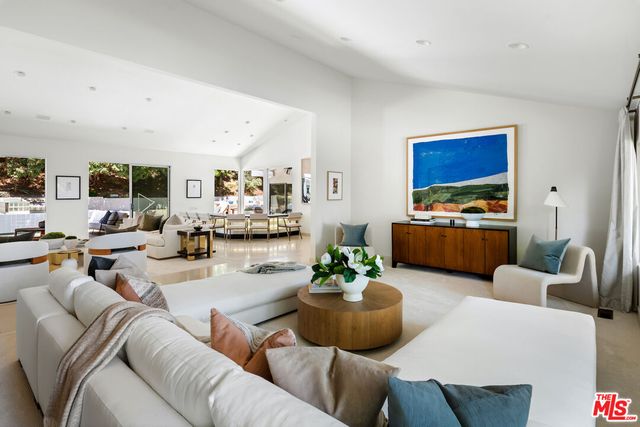 a living room with furniture kitchen view and a large window
