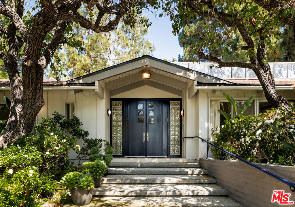 811 North Hillcrest Road Beverly Hills, CA 90210 - Photo 3 of 28 a front view of a house with a garden