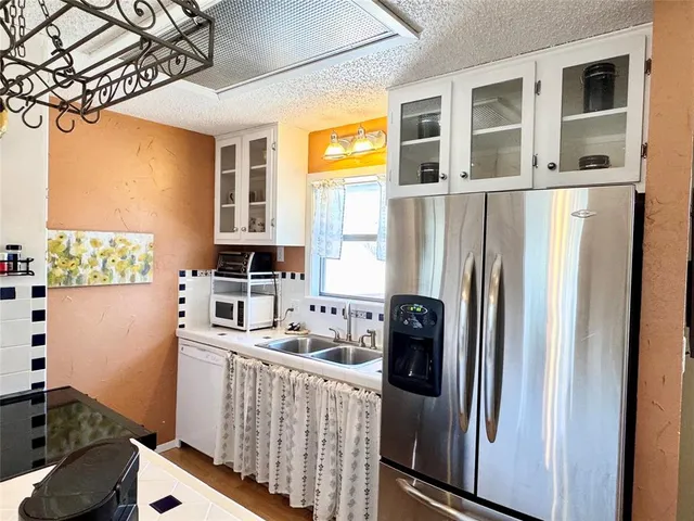 a kitchen with stainless steel appliances granite countertop a refrigerator a sink a stove and a refrigerator