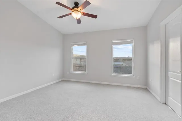 an empty room with windows and fan