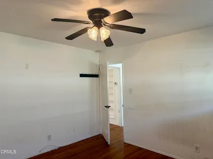 an empty room with wooden floor and ceiling fan