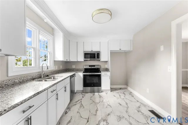 a kitchen with granite countertop a sink stainless steel appliances and white cabinets