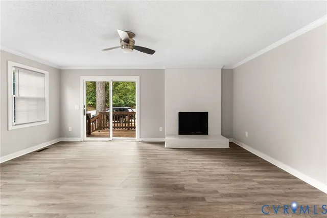 an empty room with wooden floor a ceiling fan and windows
