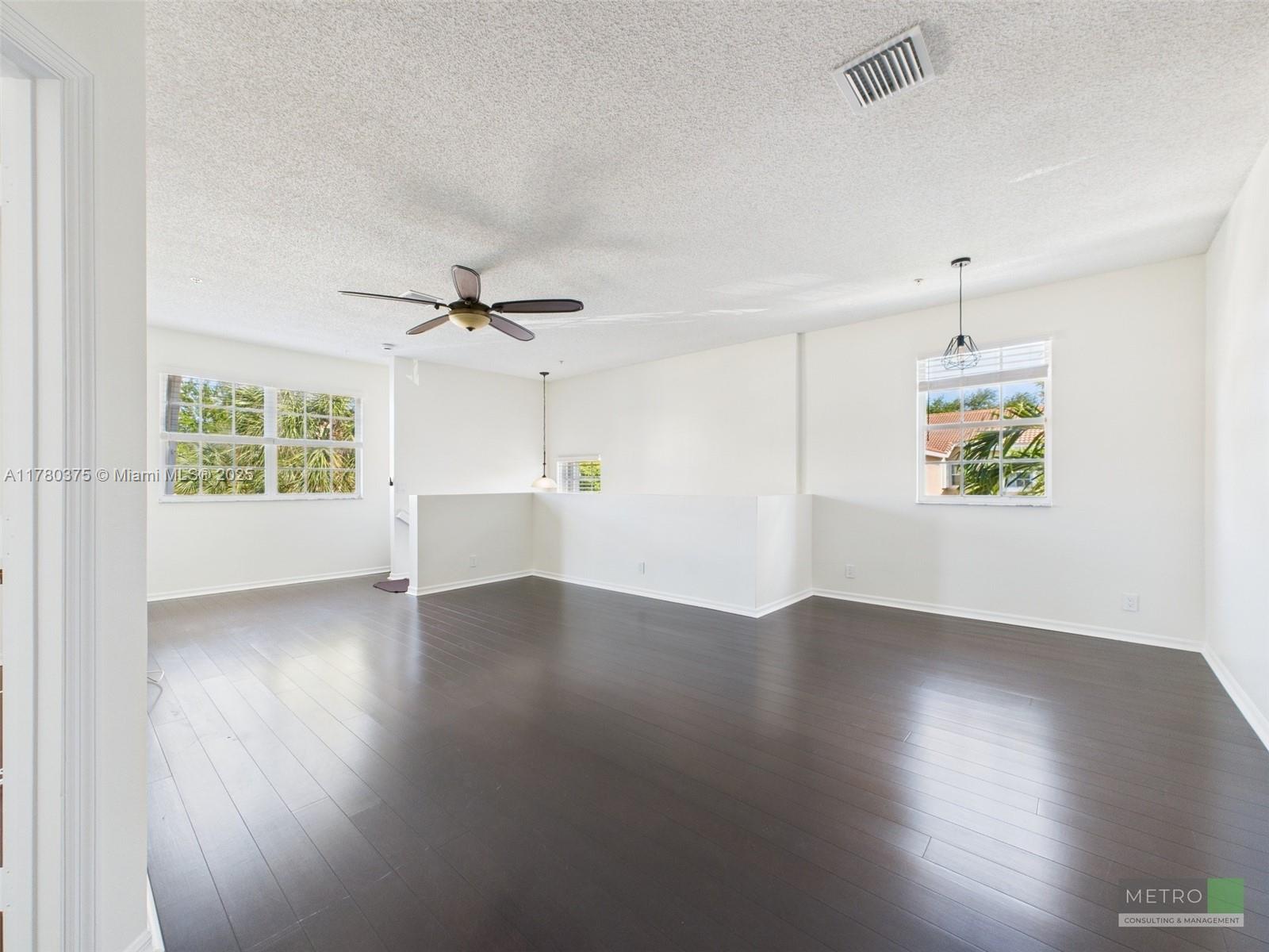 112 Lighthouse Circle, Unit H Tequesta, FL 33469 - Photo 8 of 20 an empty room with wooden floor chandelier and windows