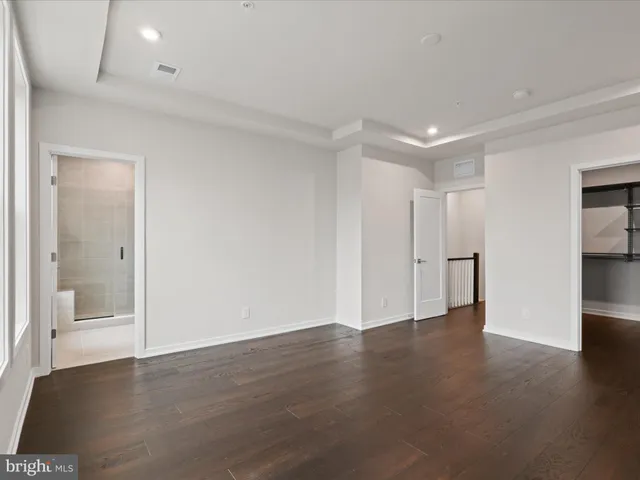 an empty room with wooden floor & windows and bathroom
