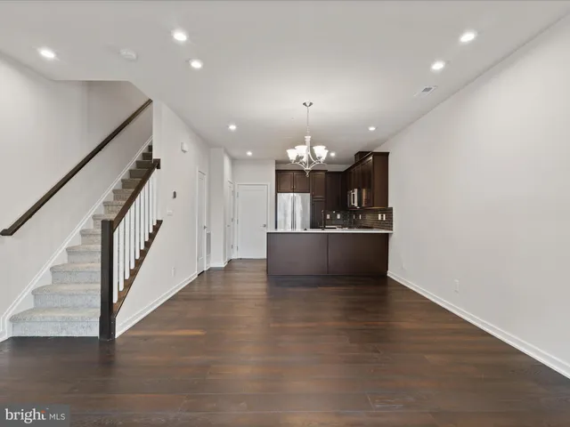 wooden floor with chandelier and kitchen view