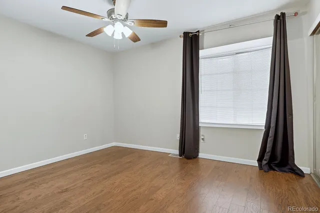 an empty room with wooden floor closet and windows