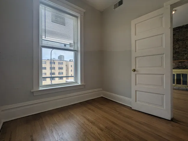 a view of an empty room with wooden floor and a window