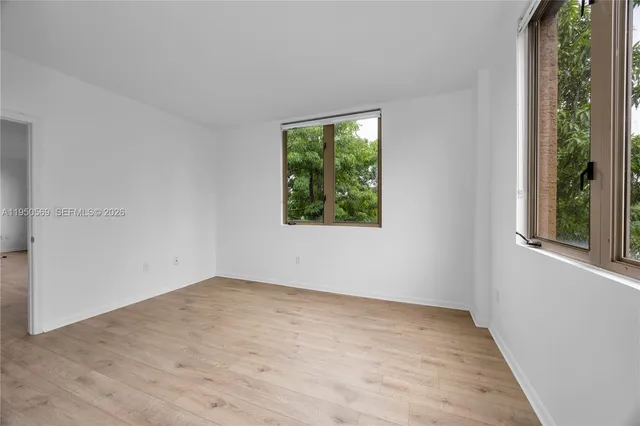 an empty room with wooden floor and windows