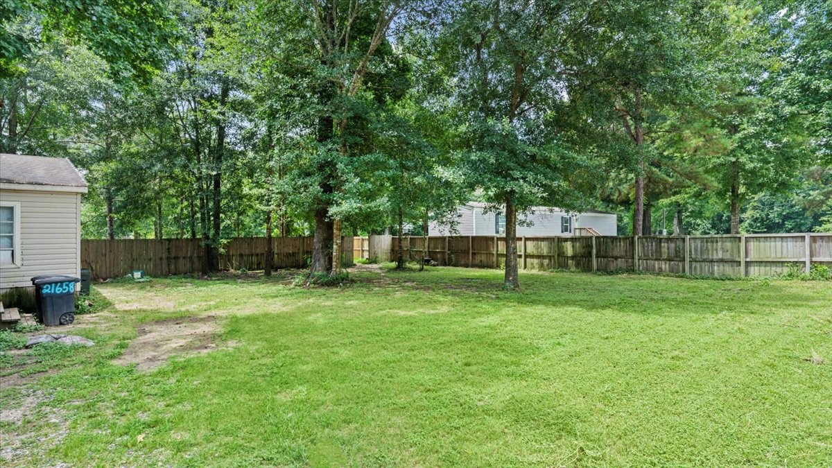 21658 County Road 3749D Cleveland, TX 77327 - Photo 4 of 26 a backyard of a house with lots of plants and large tree