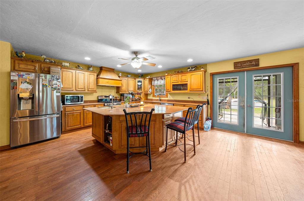 732 Carl Wilson Road Fort White, FL 32038 - Photo 3 of 80 a kitchen with stainless steel appliances kitchen island granite countertop a refrigerator a stove a sink a dining table and chairs with wooden floor