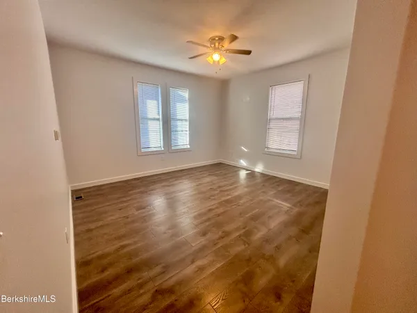 a view of an empty room with a window and wooden floor
