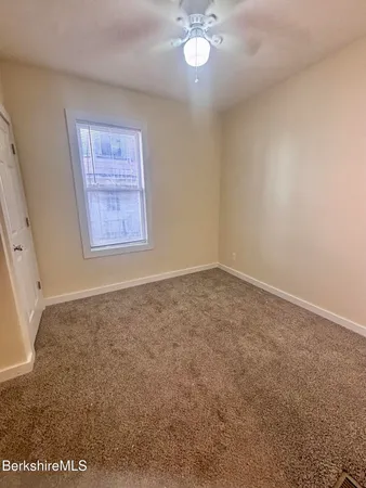 an empty room with a chandelier fan and windows