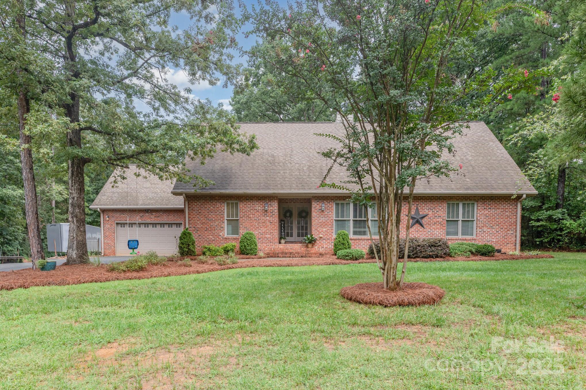 a front view of a house with a yard and a tree