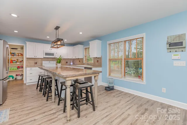 a kitchen with stainless steel appliances a dining table chairs and wooden floor