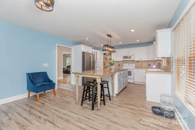 a kitchen with a table chairs a sink dishwasher stove and cabinets with wooden floor