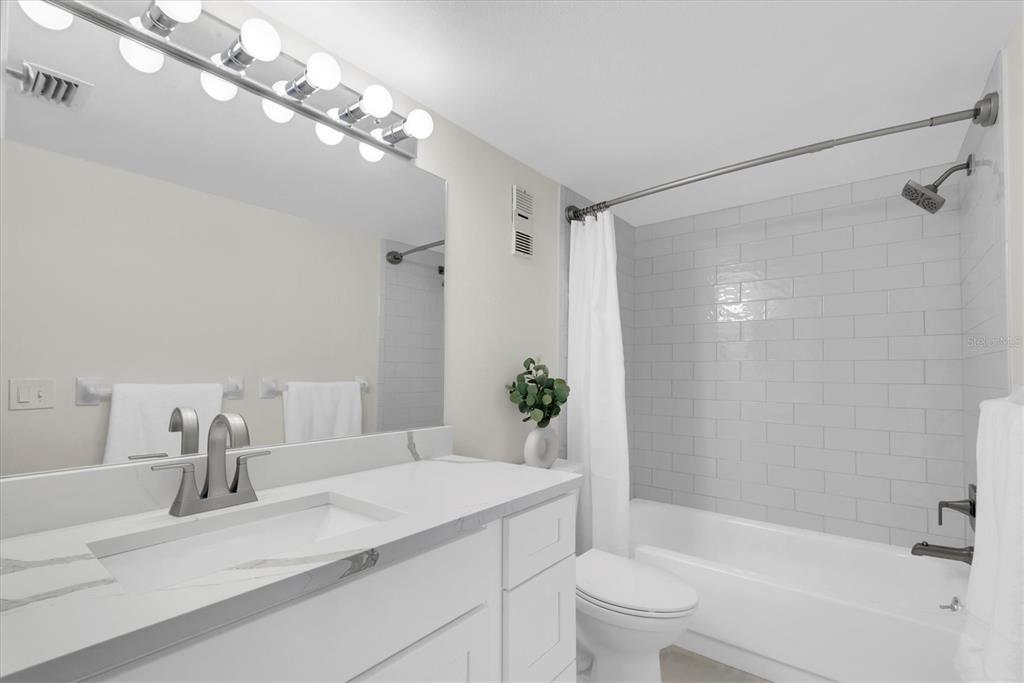 8 Glencoe Place, Unit 105 Dunedin, FL 34698 - Photo 15 of 44 a bathroom with a granite countertop sink a toilet and shower